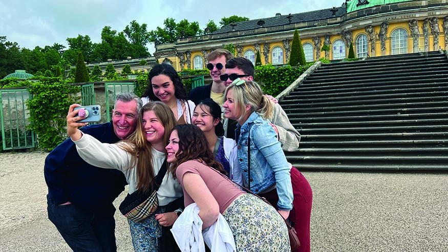 365体育投注_365体育备用网址@ Choir Director Dr. Jon Hurty and students?outside Sanssouci Palace in Potsdam, Germany.