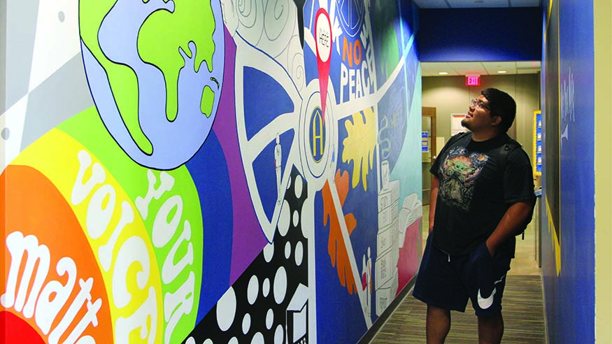 Sophomore Jesus Murillo in front of the You Belong Here Lounge mural